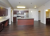 Thumbnail 3 of 10 - A kitchen with dark wood floors and white walls.