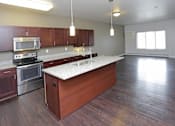 Thumbnail 5 of 10 - A kitchen with wooden cabinets and a stainless steel oven.