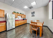 Thumbnail 10 of 13 - A community room kitchen with a table and chairs.