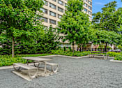 Thumbnail 13 of 13 - A picnic table sits in the middle of a gravel area with a building in the background.
