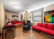 Thumbnail 4 of 15 - A living room with a red couch and a black chair.