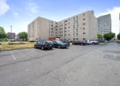 Thumbnail 2 of 22 - a parking lot with cars in front of a large building