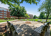 Thumbnail 6 of 25 - a park with benches and trees in front of a building