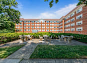 Thumbnail 1 of 25 - a picnic area with benches in front of a brick building