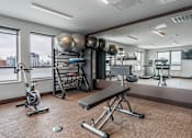 Thumbnail 12 of 25 - a fitness room with weights and exercise equipment and large windows
