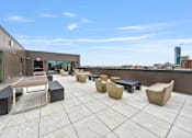 Thumbnail 24 of 25 - a rooftop patio with tables and benches and a view of the city