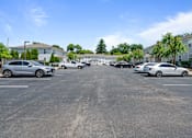 Thumbnail 5 of 23 - a parking lot with cars in front of apartment buildings