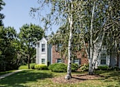 Thumbnail 9 of 19 - Exterior of Westridge Gardens with tall tress, freshly cut grass, and a walking path