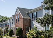 Thumbnail 11 of 19 - Exterior of Westridge Gardens with tall tress and beautiful bushes on a sunny day