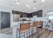 Thumbnail 7 of 44 - a kitchen with a long island with bar stools and a stainless steel refrigerator