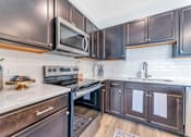 Thumbnail 9 of 44 - a kitchen with stainless steel appliances and dark wood cabinets
