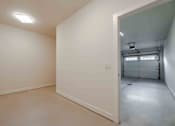 Thumbnail 48 of 49 - A white room with a doorway leading to another room.