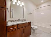 Thumbnail 14 of 49 - A bathroom with a marble countertop and a walk-in shower.