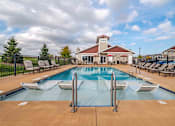 Thumbnail 25 of 49 - A large outdoor pool with a diving board and lounge chairs.