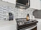 Thumbnail 3 of 230 - A modern kitchen with a black stove top oven and a black microwave above it.