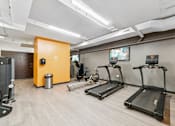 Thumbnail 129 of 230 - A gym with treadmills, a weight machine, and a TV.