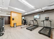 Thumbnail 13 of 230 - A gym with treadmills, a weight machine, and a TV.