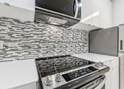 Thumbnail 79 of 230 - A modern kitchen with a stove top oven and microwave above it.