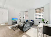 Thumbnail 55 of 230 - A living room with a grey couch and a television.