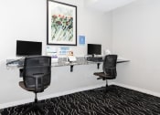 Thumbnail 31 of 45 - a office with two desks with computers and a painting on the wall