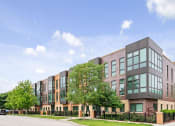 Thumbnail 23 of 59 - A modern building with a black fence in front.