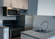 Thumbnail 8 of 17 - Cedarvale Studio Elite Kitchen with stainless steel finishes for the microwave, oven, and refrigerator, and view of the plank wood flooring