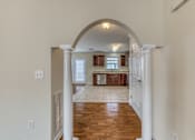 Thumbnail 3 of 9 - A hallway with a white archway leading to a kitchen.