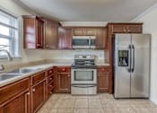Thumbnail 9 of 9 - A kitchen with wooden cabinets and a stainless steel refrigerator.