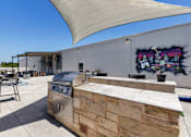 Thumbnail 12 of 18 - A barbecue grill is on a patio with a mural on the wall.
