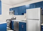 Thumbnail 11 of 19 - Modern kitchen with blue cabinets and stainless appliances at Dominion Towers Apartments, Virginia, 22204