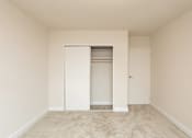 Thumbnail 17 of 19 - Empty bedroom with open closet and carpeting at Dominion Towers Apartments, Virginia