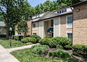 Thumbnail 9 of 23 - A building with a green awning is surrounded by bushes and trees at Potomac Ridge Apartments, Woodbridge, Virginia