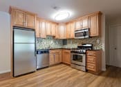Thumbnail 17 of 23 - A kitchen with wooden cabinets and a tile backsplash at Potomac Ridge Apartments, Woodbridge