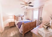Thumbnail 28 of 33 - Bedroom with wooden furniture and ceiling fan at Cantera Apartments, El Paso, 79935