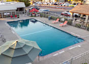 Thumbnail 2 of 33 - Swimming pool with umbrellas and concrete deck at Cantera Apartments, El Paso, Texas