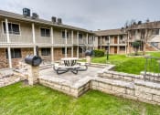 Thumbnail 8 of 36 - a patio with a table and a fire pit in front of at Juniper Springs Apartments, Austin, TX