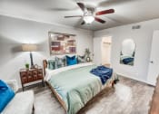 Thumbnail 13 of 36 - the master bedroom has a large bed and a ceiling fan at Juniper Springs Apartments, Austin, TX