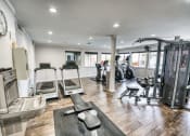 Thumbnail 18 of 36 - a gym with cardio equipment and weights on the floor at Juniper Springs Apartments, Austin, TX