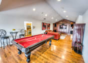 Thumbnail 3 of 36 - a game room with a red pool table and a red couch at Juniper Springs Apartments, Austin, TX