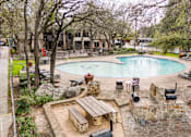 Thumbnail 8 of 37 - Outdoor pool area with stone fire pit seating at Le Montreaux Apartments, Austin, Texas