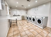 Thumbnail 36 of 37 - Community laundry room with front loading washers and dryers at Le Montreaux Apartments, Texas
