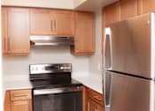 Thumbnail 7 of 34 - A modern kitchen with a stainless steel refrigerator and black stove.