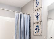 Thumbnail 12 of 17 - A white toilet with a blue shower curtain in the background.