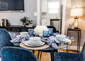Thumbnail 5 of 17 - A dining table set with blue chairs and a white flower centerpiece.