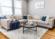 Thumbnail 4 of 17 - A living room with a beige couch, a coffee table, and a blue throw blanket.