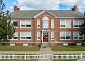 Thumbnail 15 of 17 - A red brick building with a white picket fence in front.