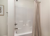Thumbnail 8 of 44 - a white bath tub sitting next to a shower curtain at Ardmore at the Trail, North Carolina