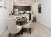 Thumbnail 2 of 44 - Dining area with a table and chairs and a kitchen in the background at Ardmore at the Trail, Indian Trail, NC 28079
