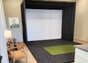 Thumbnail 4 of 5 - A room with a black screen and a green rug.