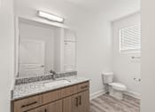 Thumbnail 27 of 30 - A bathroom with a sink, mirror, toilet and wooden cabinets.